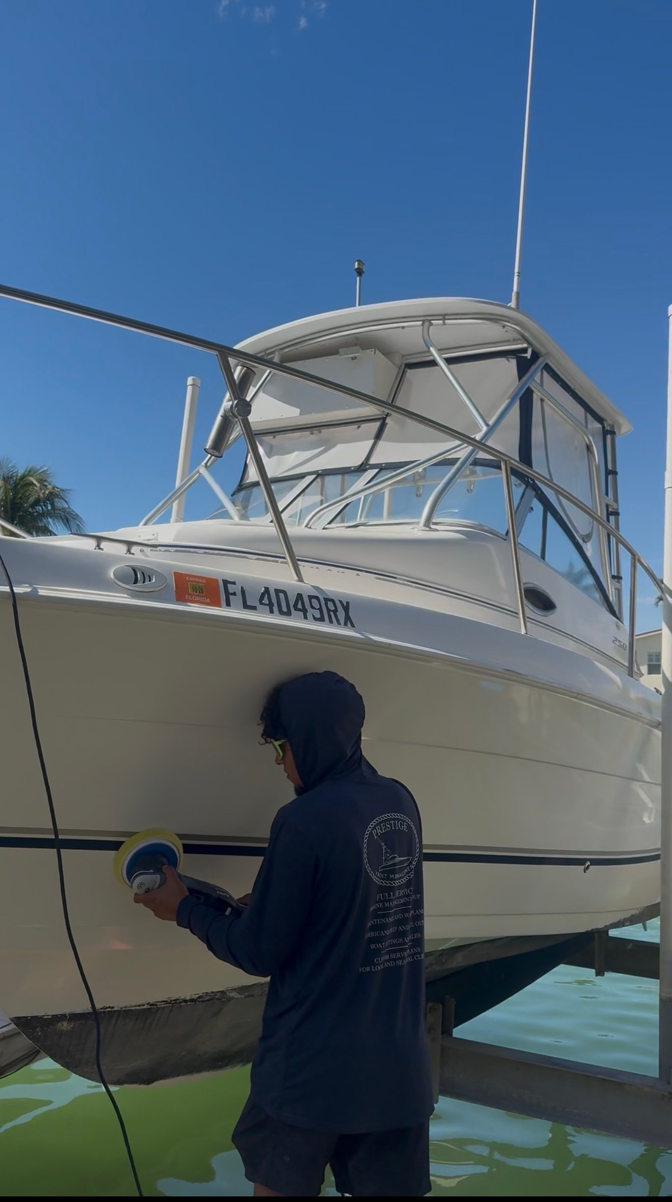 Platinum Coast Detailers technician polishing a walkaround yacht hull in Naples, Florida